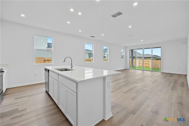 kitchen with dishwasher, sink, light wood-type flooring, an island with sink, and white cabinetry