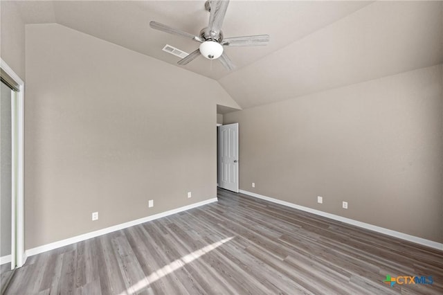 unfurnished bedroom featuring wood finished floors, baseboards, lofted ceiling, and visible vents