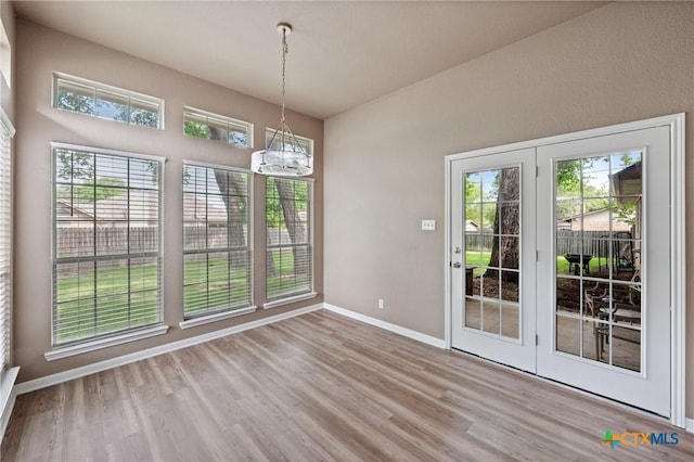 unfurnished dining area featuring baseboards, an inviting chandelier, and wood finished floors