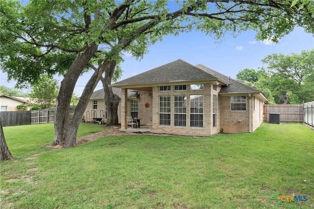 back of house featuring a shingled roof, brick siding, a fenced backyard, central air condition unit, and a lawn
