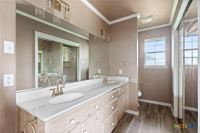 bathroom with a sink, ornamental molding, toilet, and wood finished floors