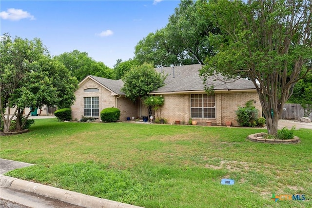 ranch-style home featuring brick siding, a front lawn, and roof with shingles