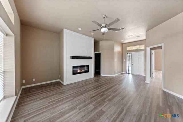 unfurnished living room with a fireplace, a ceiling fan, baseboards, recessed lighting, and wood finished floors