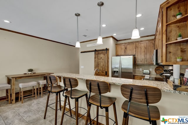 kitchen featuring pendant lighting, stainless steel appliances, a barn door, and tasteful backsplash