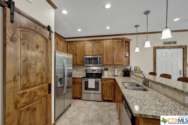 kitchen featuring stainless steel appliances, sink, kitchen peninsula, decorative light fixtures, and a barn door