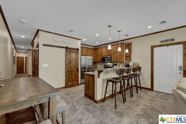 kitchen featuring kitchen peninsula, light stone counters, appliances with stainless steel finishes, a barn door, and pendant lighting