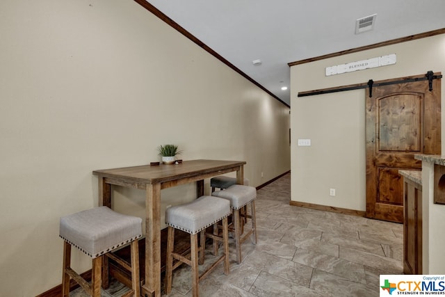 dining space featuring a barn door and crown molding