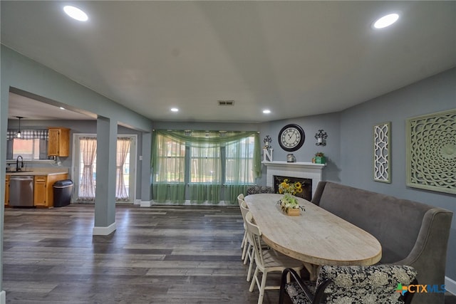 dining space featuring dark hardwood / wood-style floors, a tile fireplace, and sink