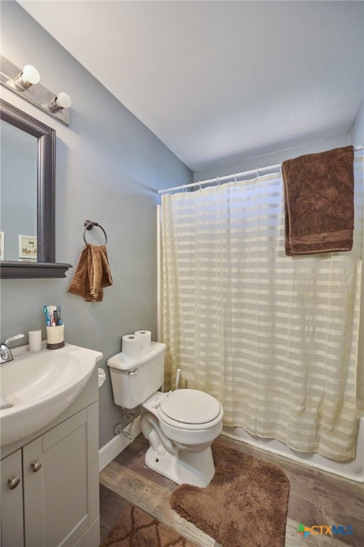 full bathroom with shower / tub combo with curtain, vanity, toilet, and hardwood / wood-style flooring