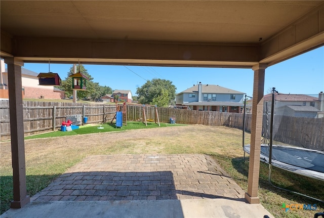 view of yard featuring a patio area, a playground, and a trampoline