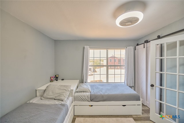 bedroom featuring a barn door and light hardwood / wood-style flooring