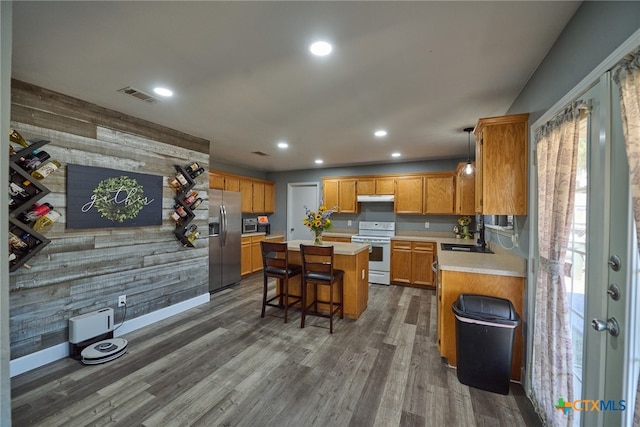 kitchen featuring a breakfast bar, white range, a center island, stainless steel fridge, and wooden walls