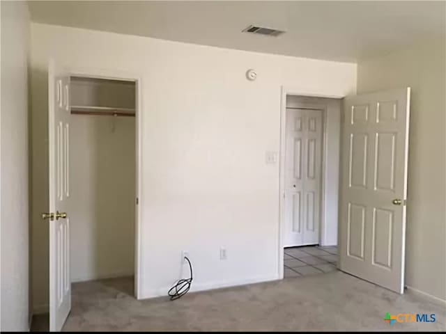 unfurnished bedroom featuring light carpet and a closet