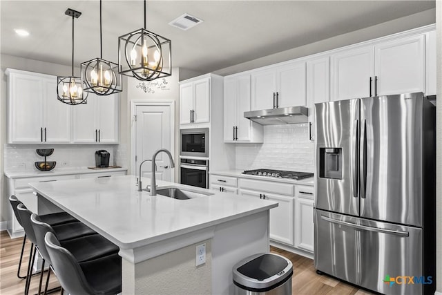 355 Victoria Peak Loop, Dripping Springs, TX 78620 - kitchen with appliances with stainless steel finishes, a sink, under cabinet range hood, a chandelier, and a kitchen island with sink