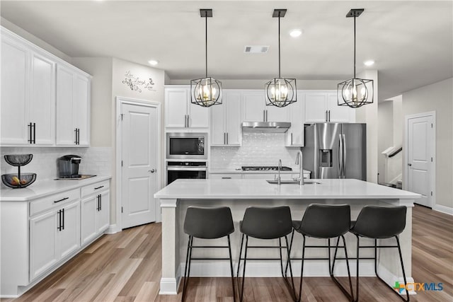 355 Victoria Peak Loop, Dripping Springs, TX 78620 - kitchen featuring stainless steel appliances, a sink, light wood finished floors, tasteful backsplash, and recessed lighting