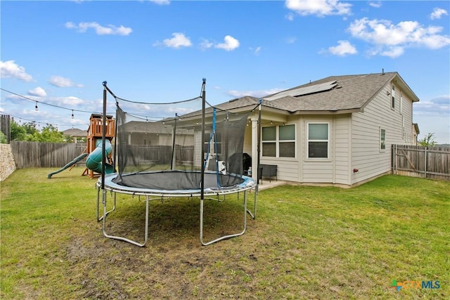 355 Victoria Peak Loop, Dripping Springs, TX 78620 - back of property featuring a trampoline, a playground, roof mounted solar panels, and a shingled roof