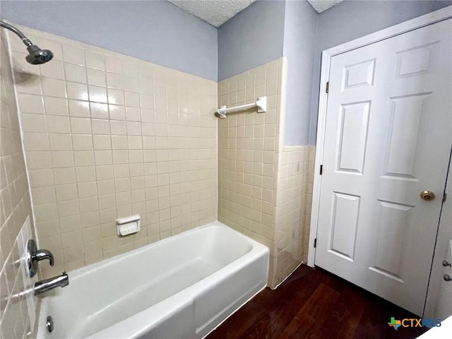 917 Edwards St, Copperas Cove, TX 76522 - bathroom with wood finished floors, bathing tub / shower combination, tile walls, a textured ceiling, and a wainscoted wall