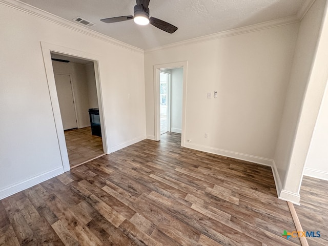 empty room featuring a textured ceiling, dark hardwood / wood-style floors, ceiling fan, and ornamental molding