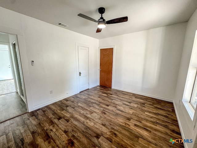 unfurnished bedroom with ceiling fan and dark wood-type flooring