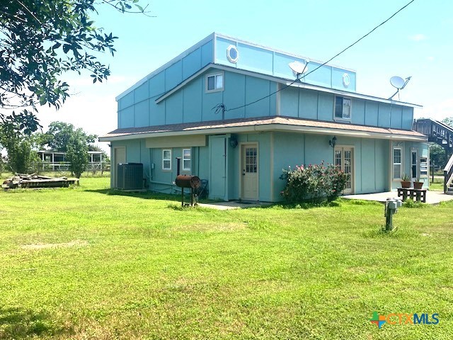 488 Alamo Beach Ave, Port Lavaca, TX 77979 - back of property featuring board and batten siding, a lawn, and central air condition unit
