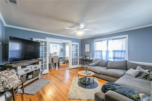 living room featuring hardwood / wood-style flooring, ceiling fan, crown molding, and french doors