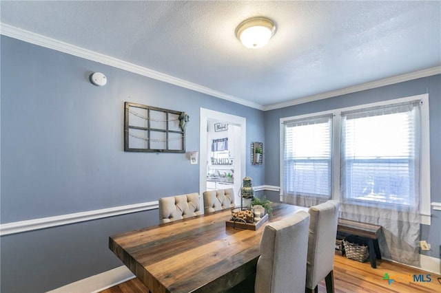 dining area with hardwood / wood-style floors, a textured ceiling, and crown molding