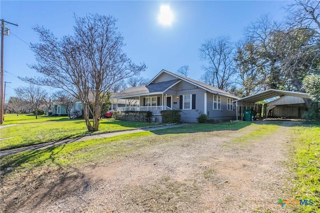 ranch-style home featuring a front lawn, a porch, and a carport