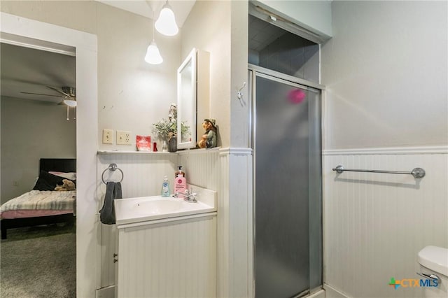 bathroom with vanity, a shower with door, ceiling fan, toilet, and wood walls