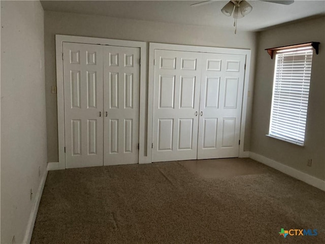 unfurnished bedroom with multiple windows, two closets, carpet floors, and ceiling fan