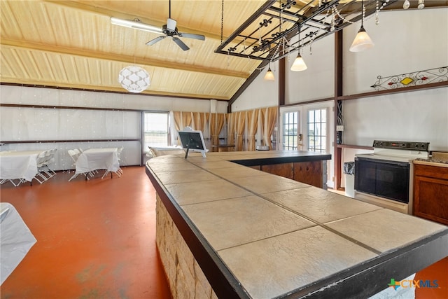 kitchen featuring ceiling fan, high vaulted ceiling, concrete flooring, range with electric cooktop, and french doors