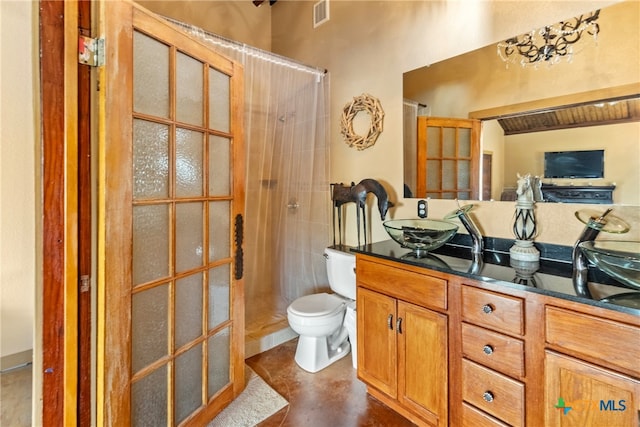 bathroom with toilet, concrete flooring, vanity, and a tile shower