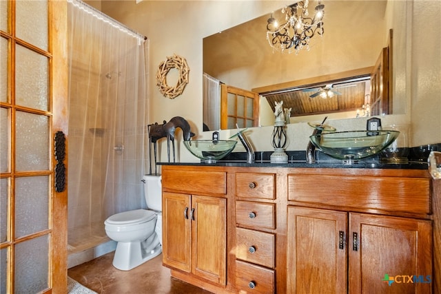 bathroom with tiled shower, ceiling fan with notable chandelier, vanity, and toilet