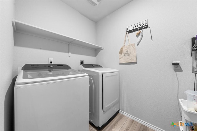 laundry area featuring laundry area, light wood-type flooring, washing machine and clothes dryer, and baseboards