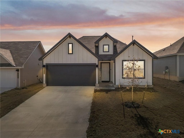 modern farmhouse style home with an attached garage, driveway, board and batten siding, and roof with shingles