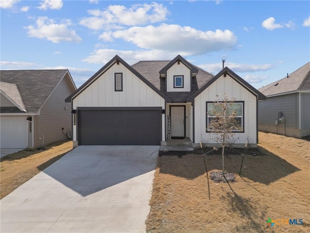 modern farmhouse featuring a garage, driveway, board and batten siding, and roof with shingles