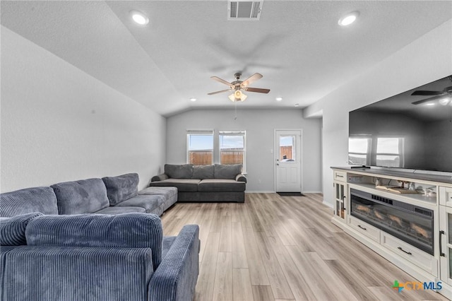 living room with lofted ceiling, ceiling fan, visible vents, baseboards, and light wood-style floors