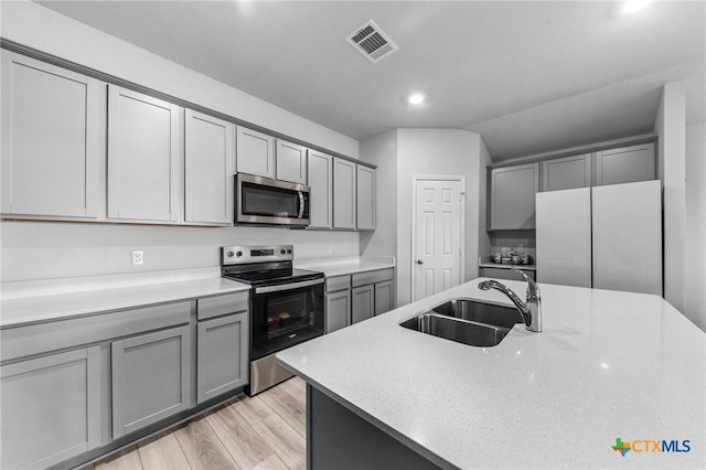 kitchen with gray cabinetry, stainless steel appliances, a sink, visible vents, and light countertops