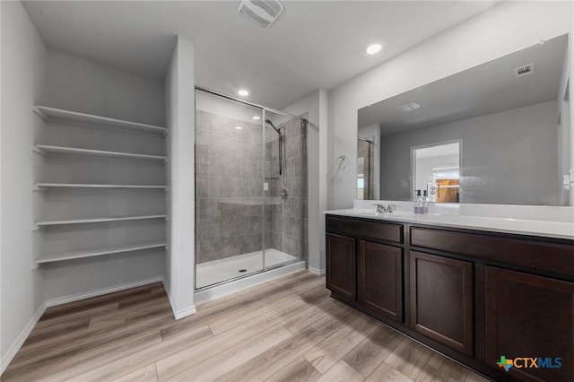 bathroom with baseboards, visible vents, wood finished floors, vanity, and a shower stall