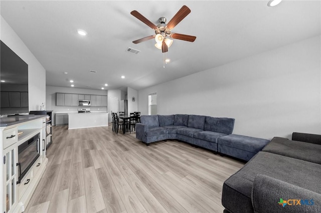 living room featuring a ceiling fan, recessed lighting, visible vents, and light wood finished floors