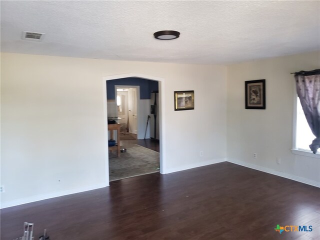 spare room with dark wood-type flooring and a textured ceiling