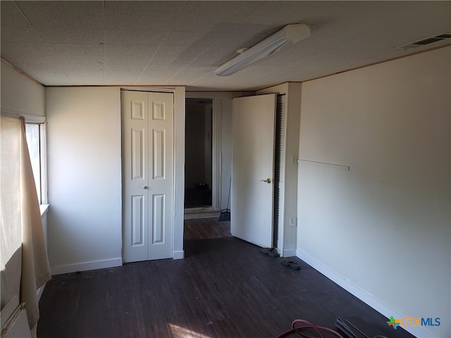 unfurnished bedroom with dark wood-type flooring and a closet