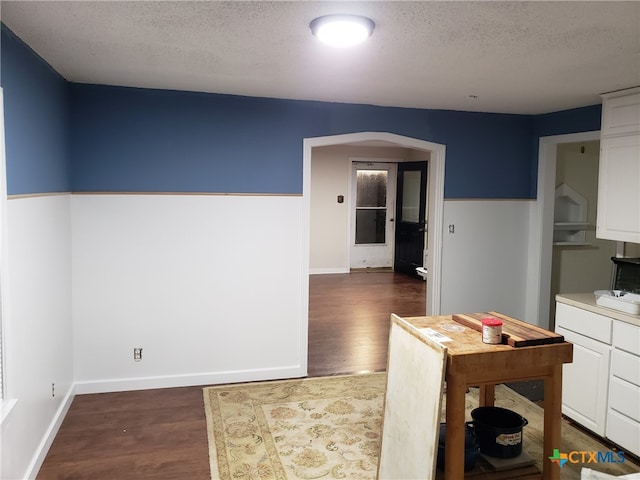 12101 Moffat Rd, Temple, TX 76502 - kitchen with dark wood-type flooring, white cabinetry, arched walkways, a textured ceiling, and baseboards