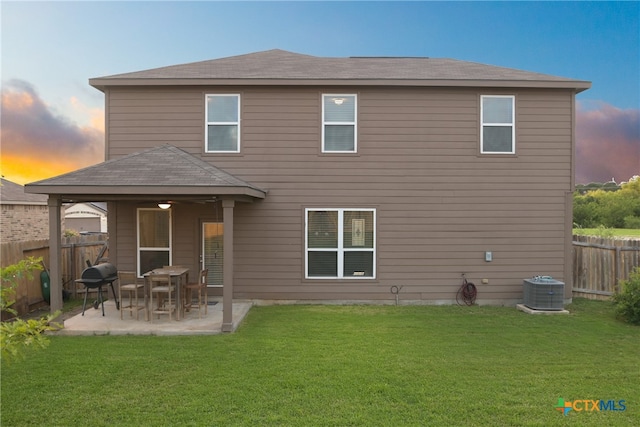 back house at dusk featuring central air condition unit, a patio area, a yard, and ceiling fan