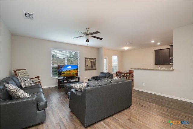 living room with dark wood-type flooring, ceiling fan, and plenty of natural light