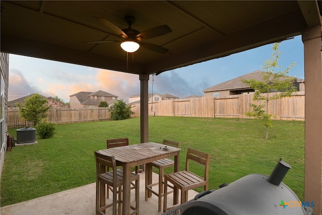 patio terrace at dusk with a lawn, central air condition unit, and ceiling fan