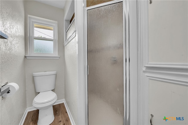 bathroom with toilet, an enclosed shower, and hardwood / wood-style flooring