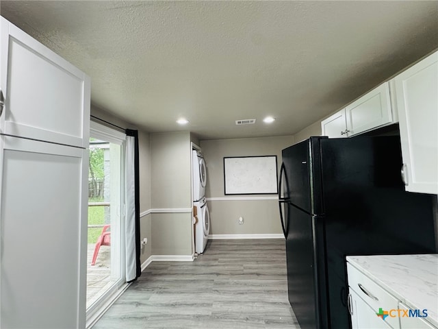 706 Golf Course Rd, Gatesville, TX 76528 - kitchen featuring stacked washer and dryer, white cabinetry, light stone counters, freestanding refrigerator, and light wood-style flooring