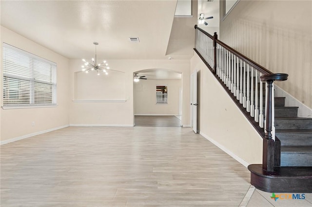 interior space featuring ceiling fan with notable chandelier and light hardwood / wood-style flooring