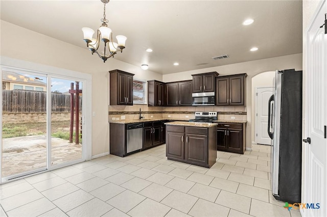 kitchen with decorative backsplash, pendant lighting, a kitchen island, and stainless steel appliances