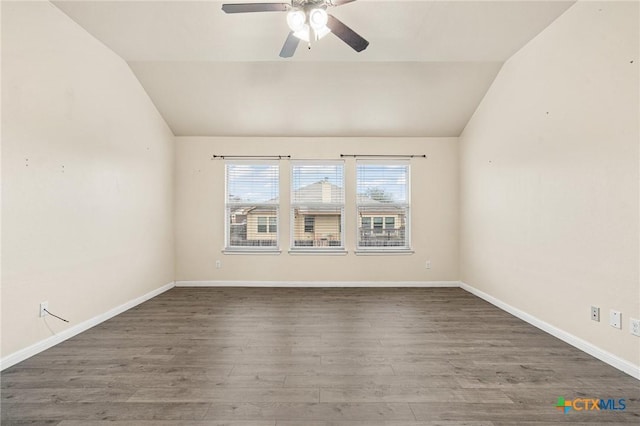 empty room with dark hardwood / wood-style flooring, vaulted ceiling, and ceiling fan